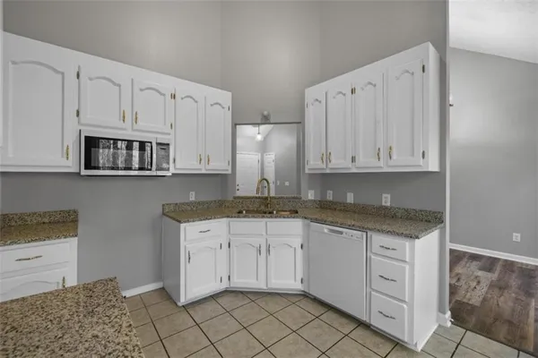 a kitchen with granite countertop white cabinets white appliances and granite counter tops