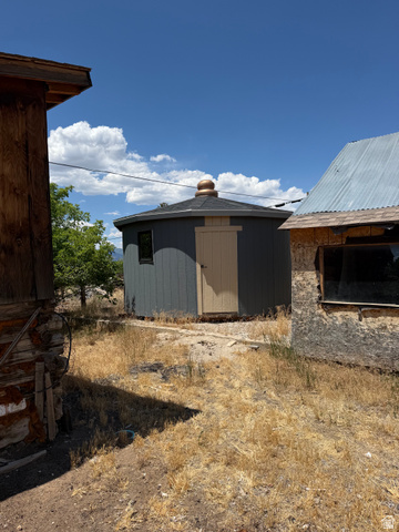 255 E Centre Spring City, UT 84662 - Photo 33 of 34 Octagonal outbuilding featuring gray siding, a light-colored door, a small window, and a dark shingle roof with a copper-toned finial