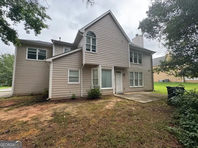 a view of a house with a yard and large tree