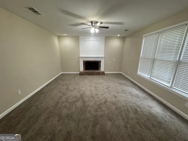 a view of an empty room with a fireplace and a window