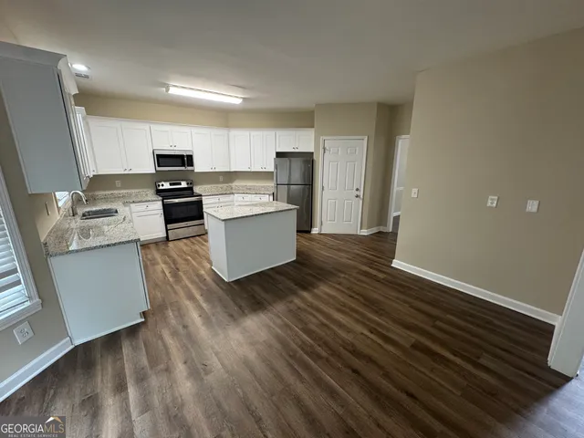 a living room with stainless steel appliances furniture and a wooden floor