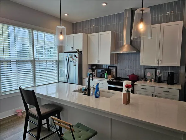 a kitchen with stainless steel appliances granite countertop a sink chairs and refrigerator