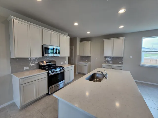 a kitchen with kitchen island a sink stainless steel appliances and cabinets