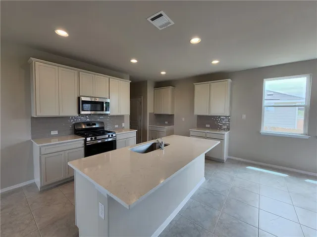 a kitchen with stainless steel appliances kitchen island sink refrigerator and cabinets