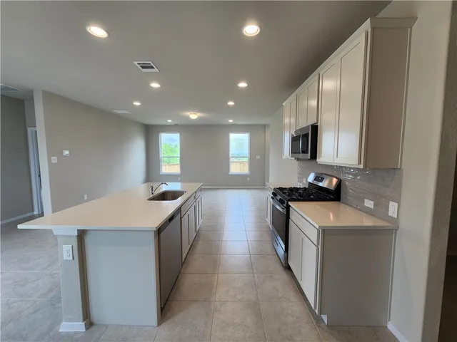 a large kitchen with kitchen island a sink a stove and a refrigerator