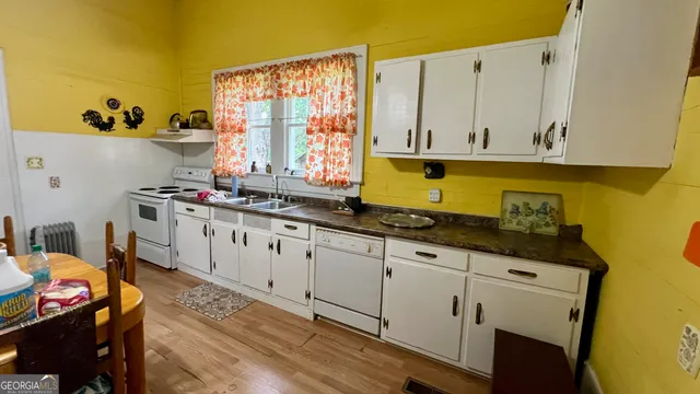 a kitchen with stainless steel appliances granite countertop a stove a sink dishwasher and a refrigerator with wooden floor