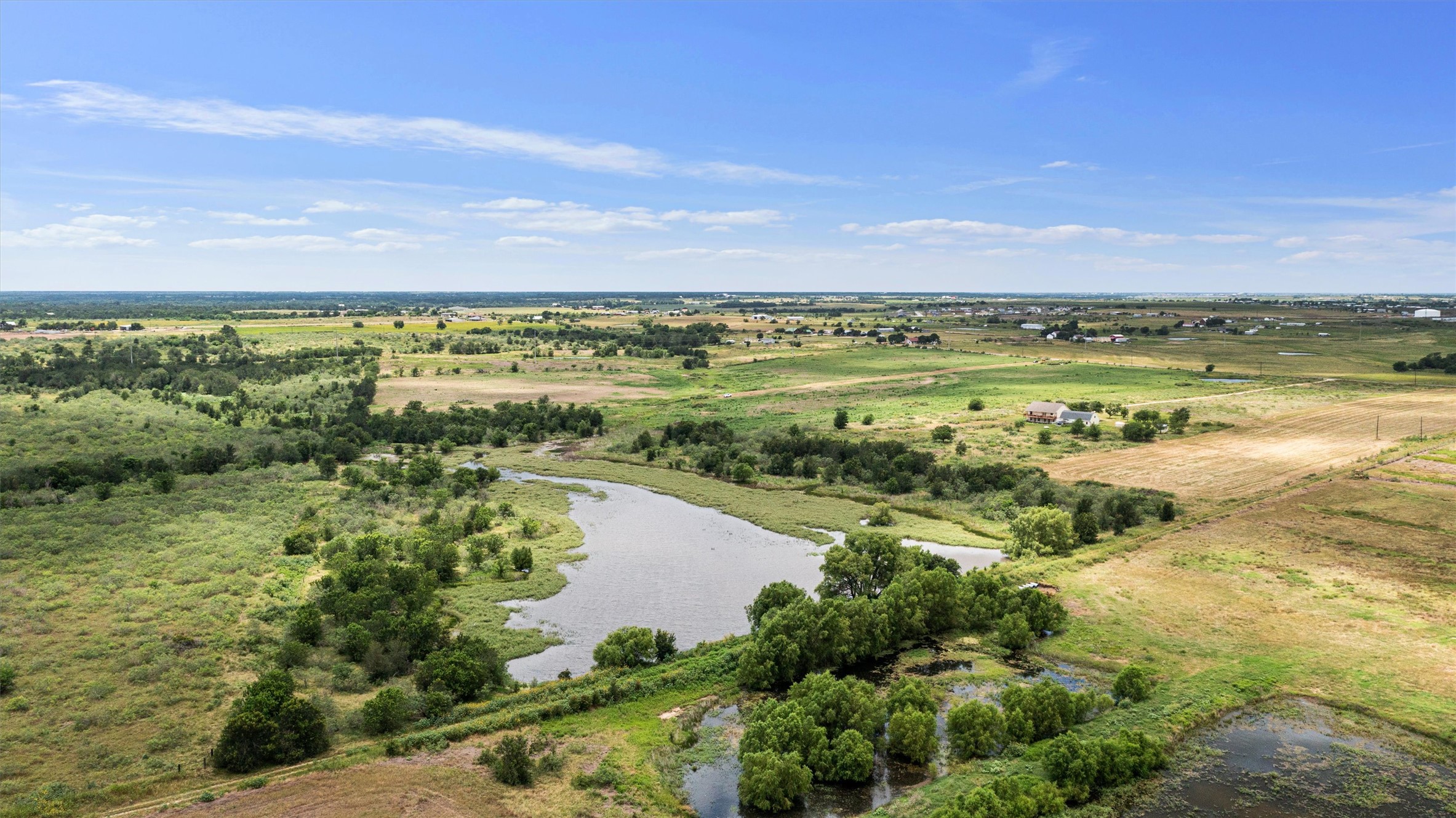 3315 County Road 463 Elgin, TX 78621 - Photo 17 of 32 Vast, open terrain offers a serene rural landscape with a tranquil body of water.