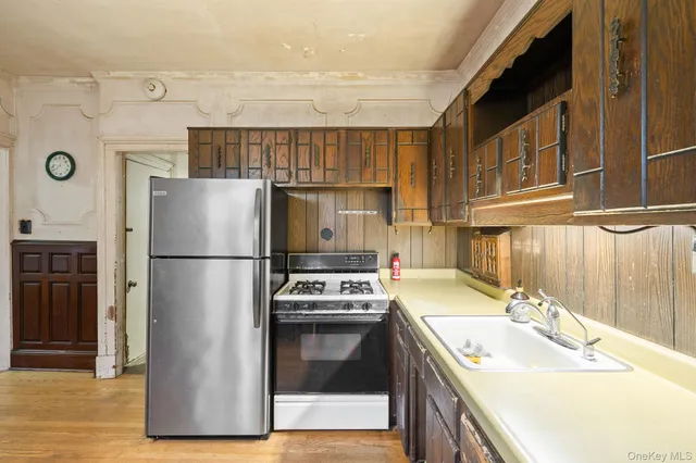 a kitchen with stainless steel appliances granite countertop a refrigerator a stove and a sink with wooden floor