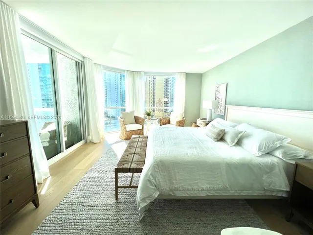 a bedroom with a bed wooden floor and a large window