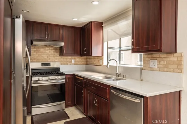 a kitchen with granite countertop wooden cabinets stove top oven and sink