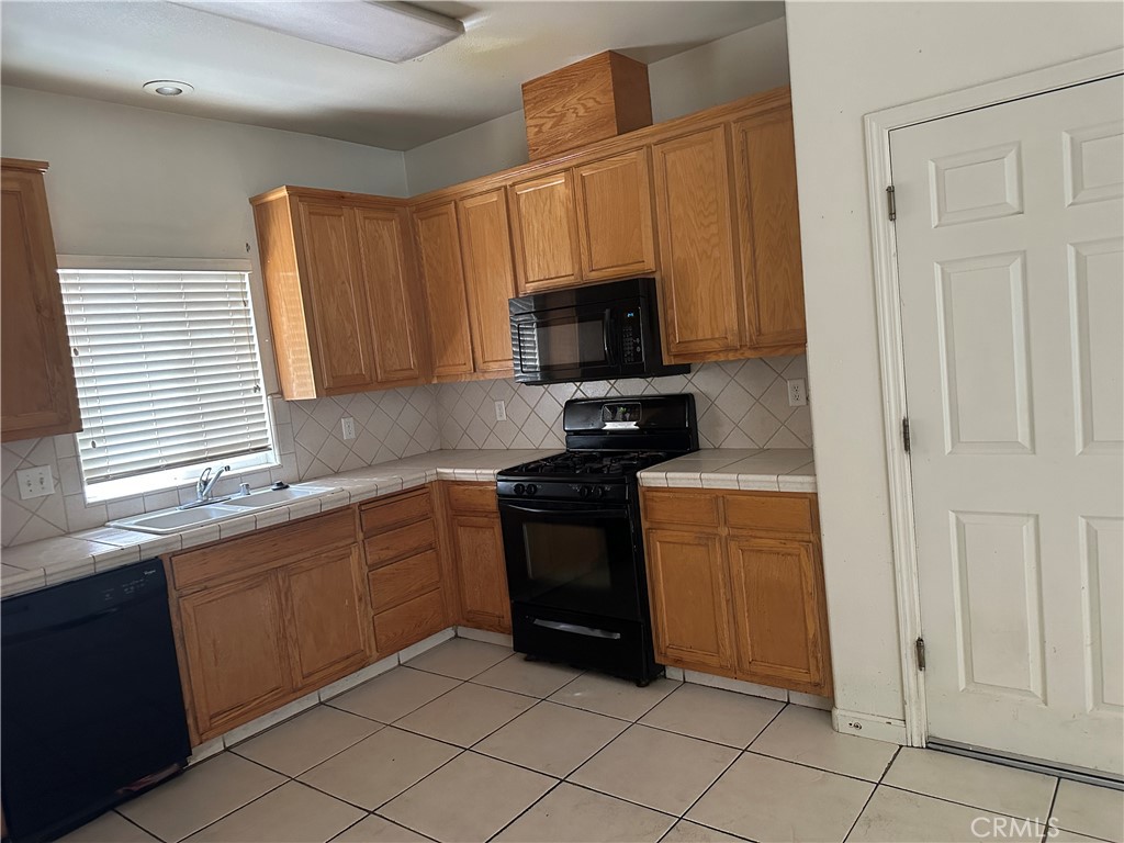 692 Gateway Circle Merced, CA 95340 - Photo 9 of 24 a kitchen with white cabinets a sink and a stove with wooden floor