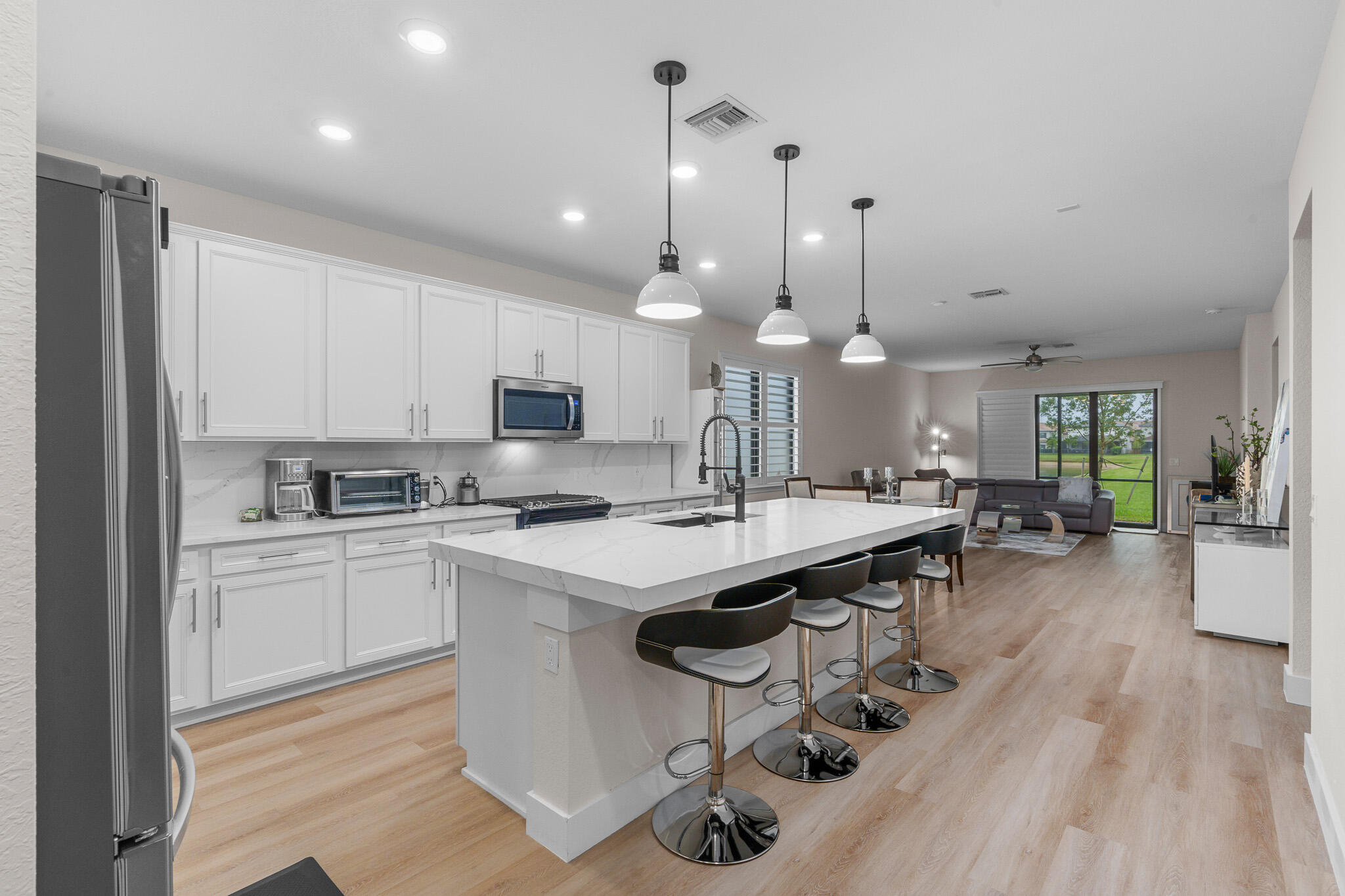 8202 Cadre Noir Road Lake Worth, FL 33467 - Photo 2 of 58 a kitchen with kitchen island a stove a table a sink a refrigerator and cabinets