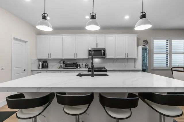 a kitchen with stainless steel appliances granite countertop a stove a sink and a refrigerator with white cabinets