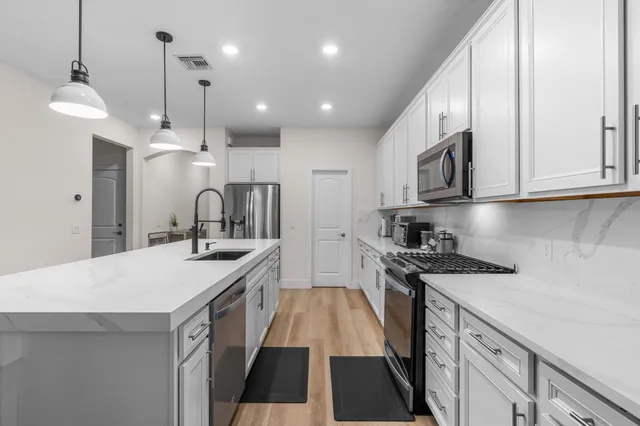 a large white kitchen with sink and stainless steel appliances
