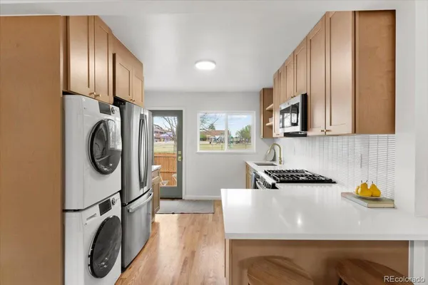 a kitchen with stainless steel appliances granite countertop a refrigerator a stove and a sink with wooden floor