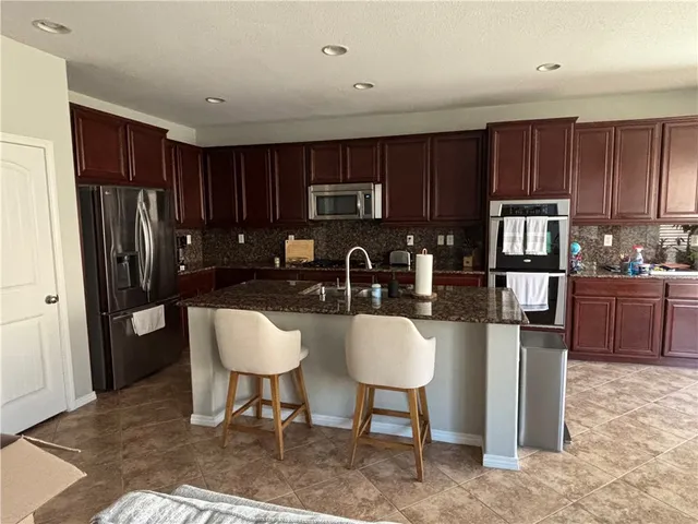 a kitchen with granite countertop a refrigerator and a stove top oven