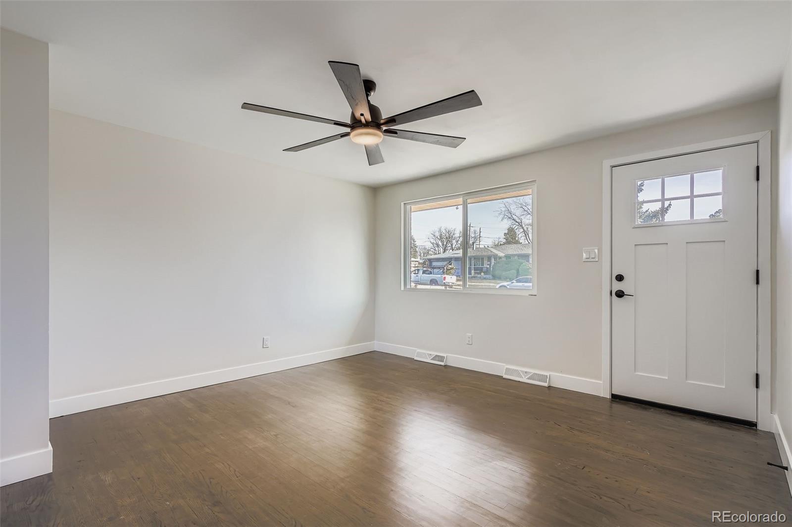 8771 Rutgers Street Westminster, CO 80031 - Photo 4 of 25 an empty room with wooden floor ceiling fan and windows