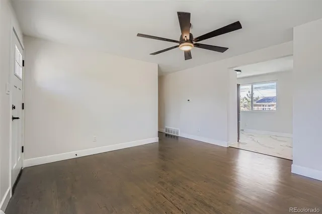an empty room with wooden floor fan and windows