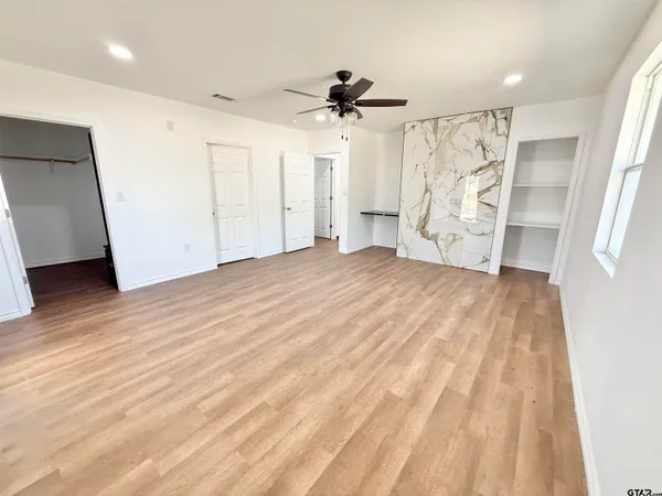 a view of empty room with wooden floor and ceiling fan