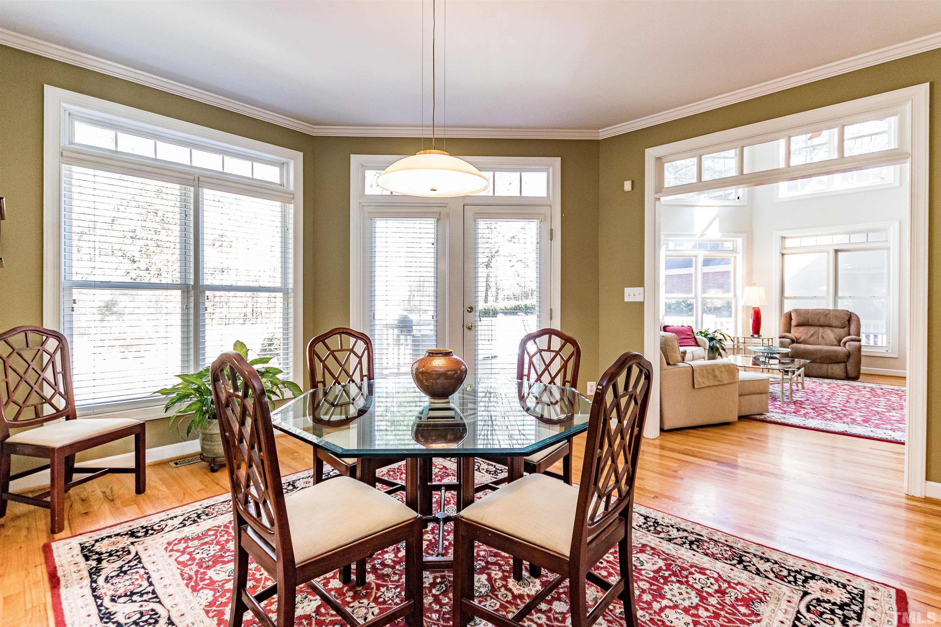 3324 Edgemont Drive Raleigh, NC 27612 - Photo 10 of 29 a dining room with furniture wooden floor a rug a flat screen tv and a large window