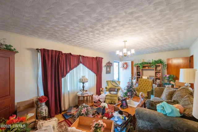 a living room with furniture a chandelier and a view of kitchen