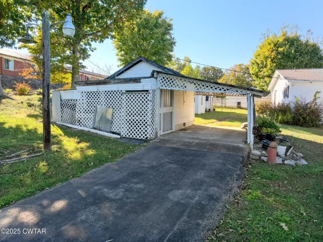 a view of a house with a yard plants and large tree