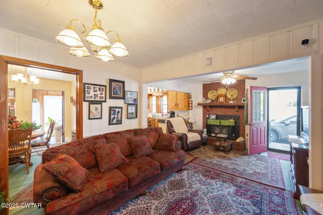 a living room with furniture a chandelier and a large mirror next to a window