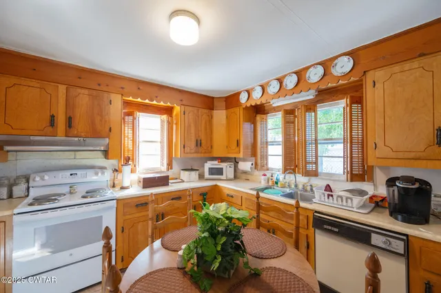 a kitchen with stainless steel appliances kitchen island granite countertop a sink dishwasher a stove and white cabinets with wooden floor