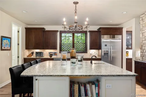 a kitchen with granite countertop a sink a center island stainless steel appliances and windows