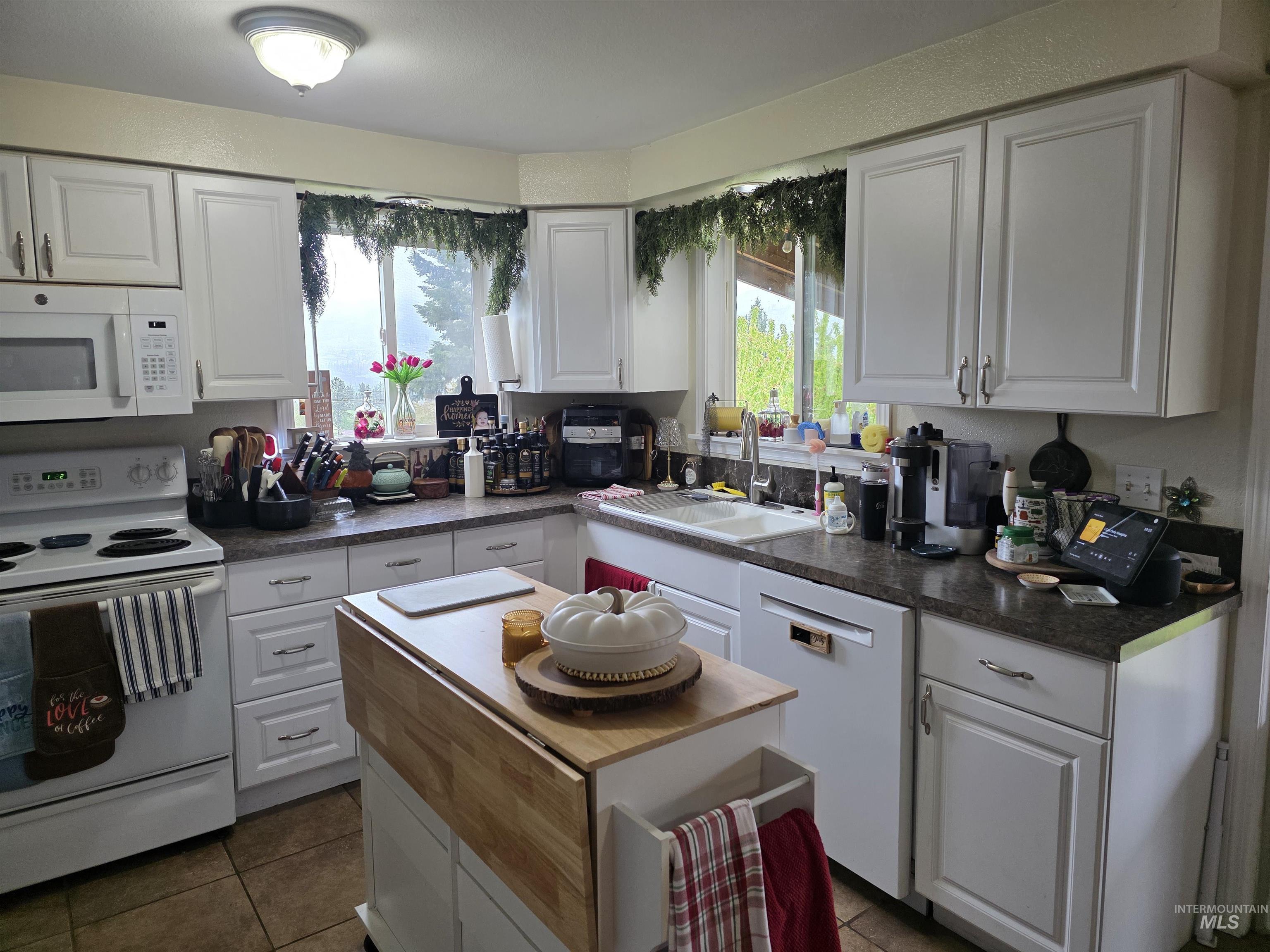 223 Larch Road Kamiah, ID 83536 - Photo 11 of 25 Bright kitchen featuring white cabinetry, a double basin sink, stone-finish countertops, and tile flooring