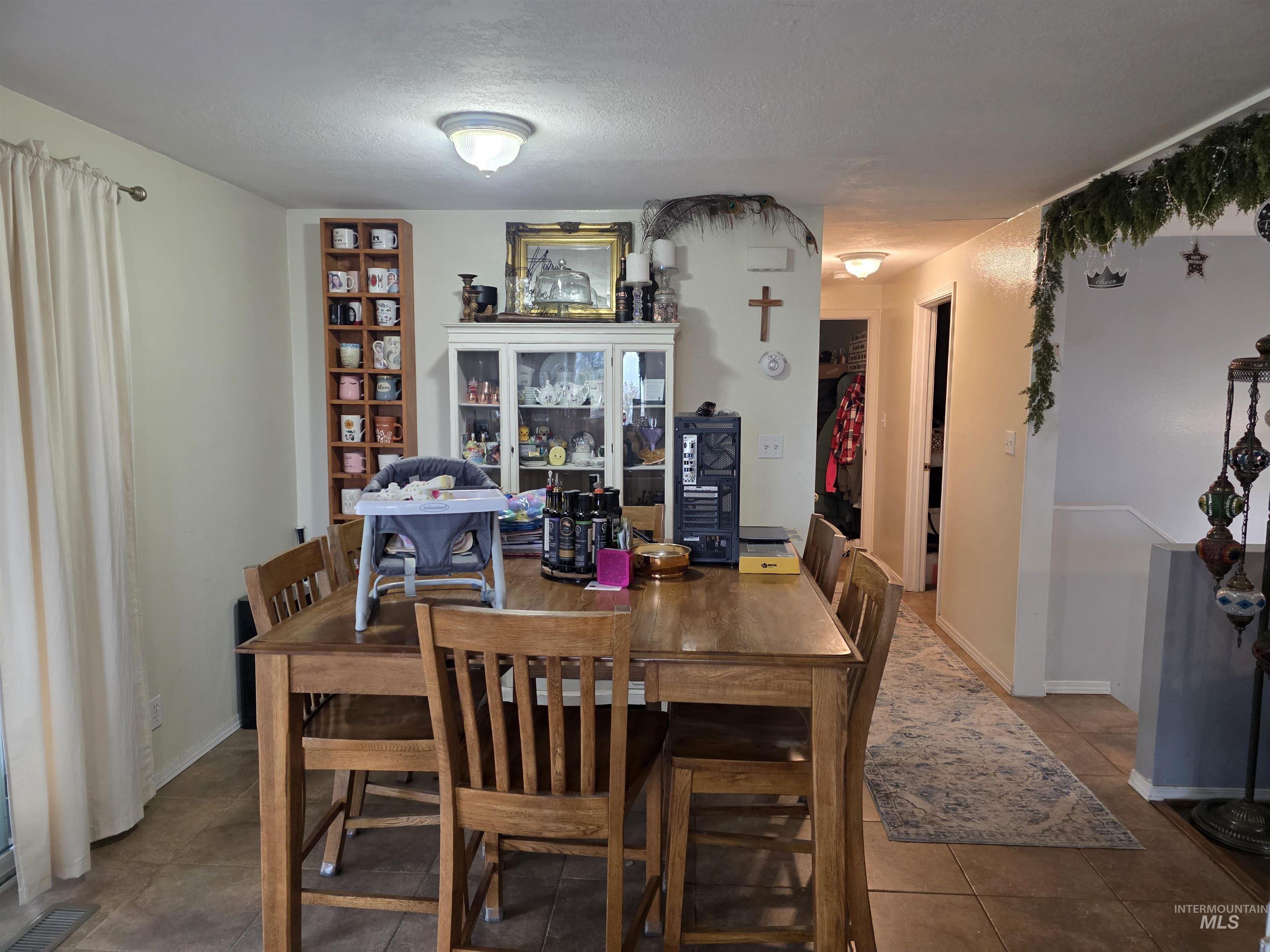 223 Larch Road Kamiah, ID 83536 - Photo 12 of 25 Dining area featuring tile flooring, neutral wall tones, and a wood-finish dining table with matching chairs