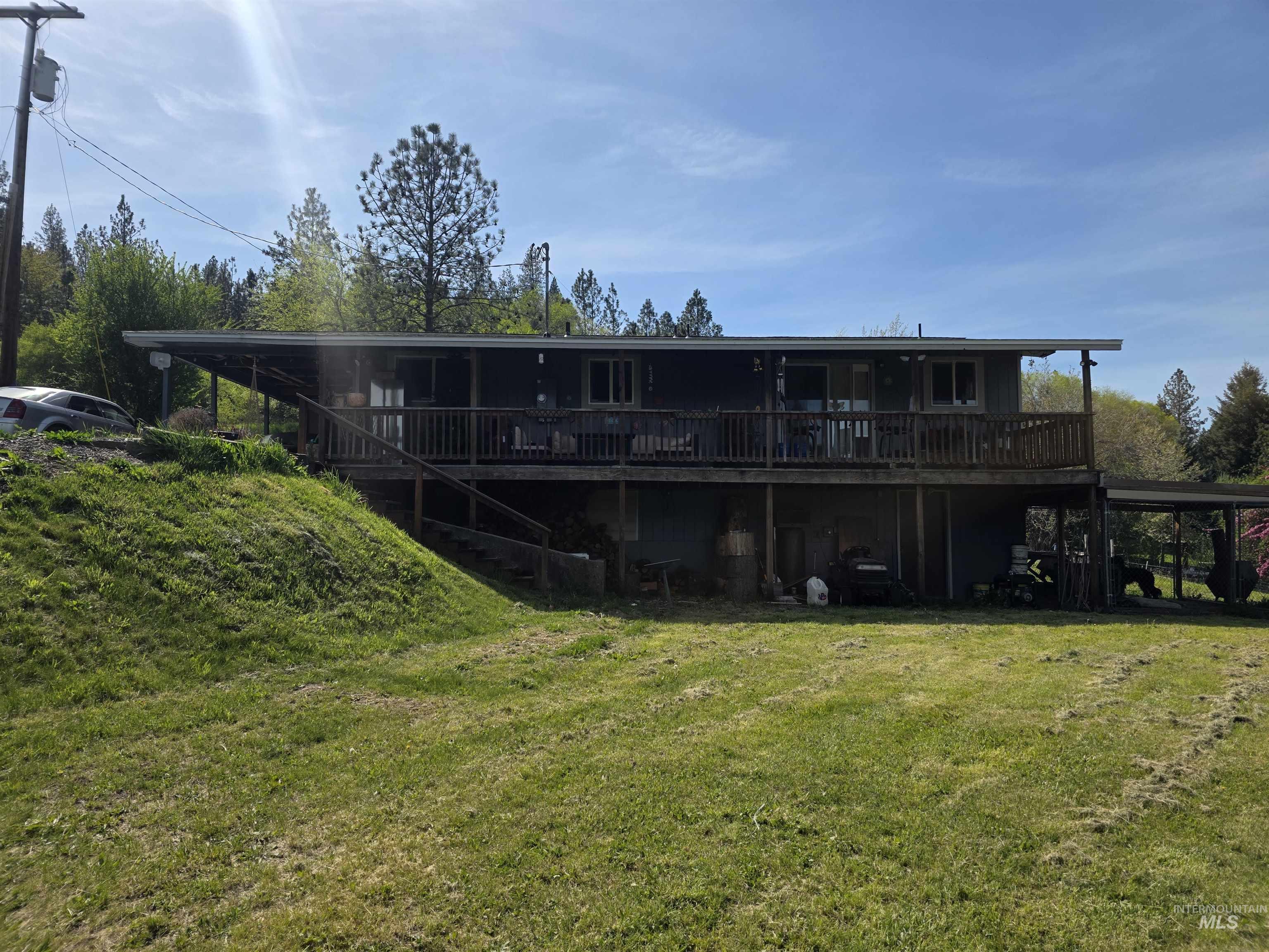 223 Larch Road Kamiah, ID 83536 - Photo 22 of 25 Multi-level residence featuring an expansive upper-level deck with wood railing, set against a backdrop of mature trees