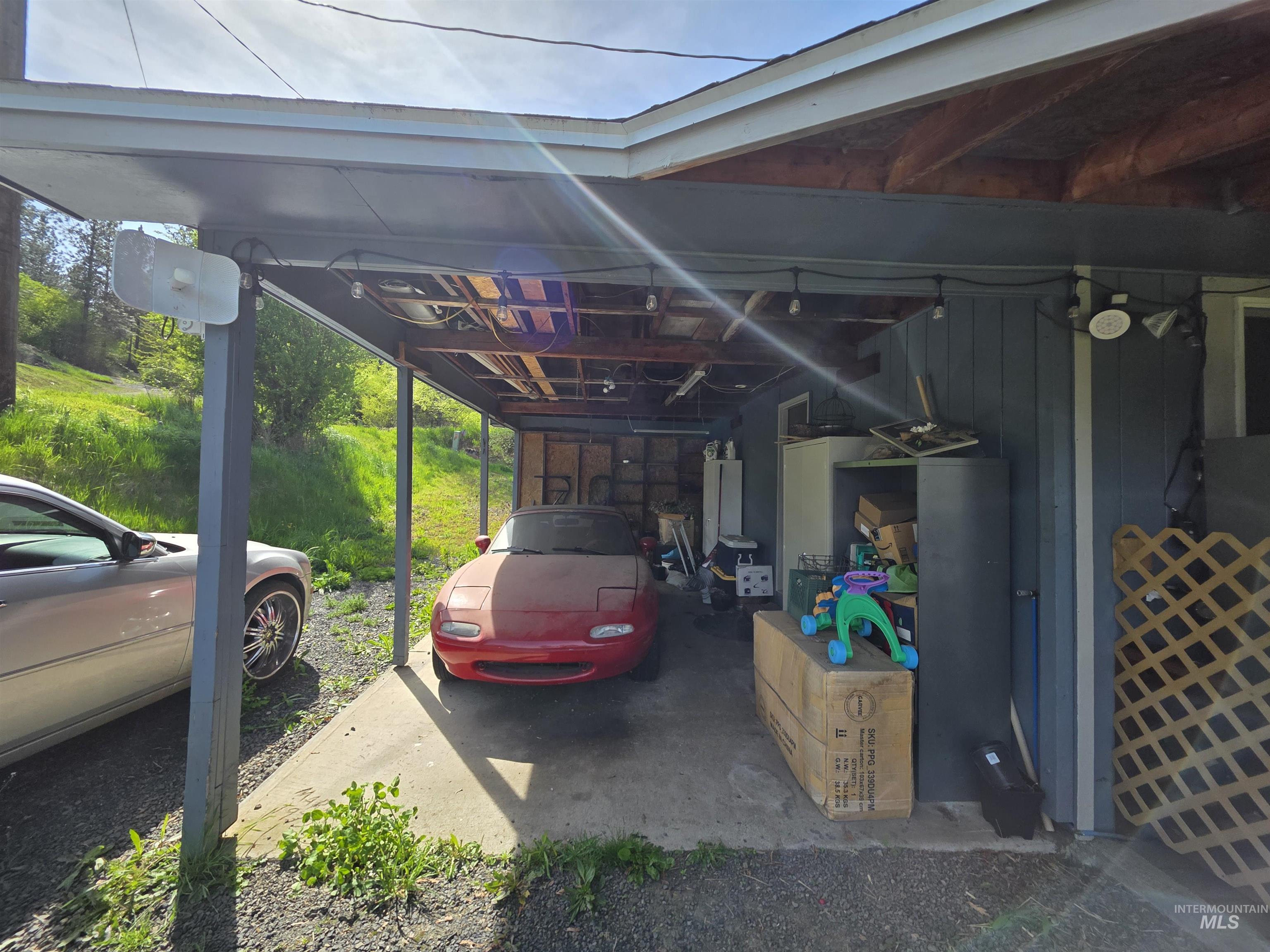 223 Larch Road Kamiah, ID 83536 - Photo 5 of 25 Carport structure with a gray finish, featuring a concrete pad and exposed wood rafter ceiling
