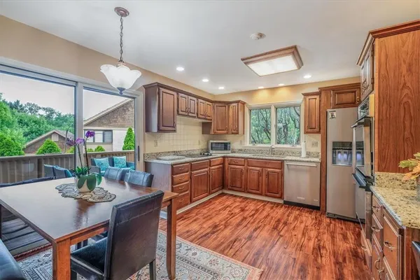 a kitchen with stainless steel appliances granite countertop a refrigerator a sink dishwasher a stove and white countertops with wooden floor