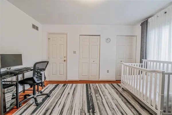 a view of a room with wooden floor book shelf and chairs