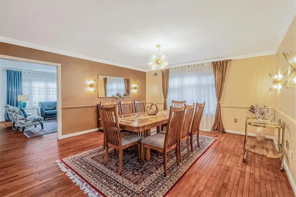 a dining room with wooden floor a chandelier a glass table and chairs