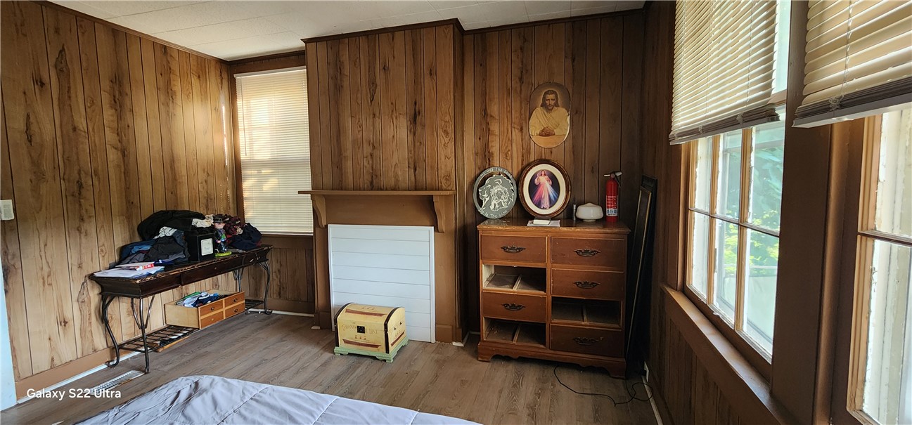 105 Hope Avenue Seneca, SC 29678 - Photo 12 of 33 Cozy bedroom with warm wood paneling and a charming decorative fireplace, offering natural light through multiple windows.