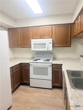 a kitchen with granite countertop a stove top oven sink and cabinets