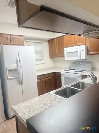 a kitchen with granite countertop a sink stainless steel appliances and window