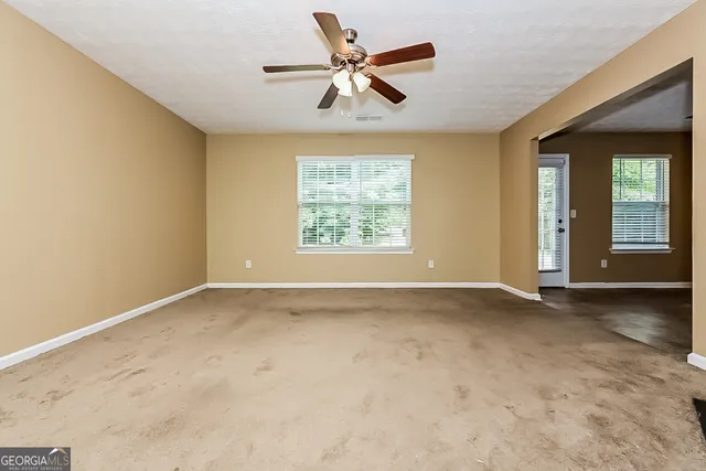 an empty room with windows and fan