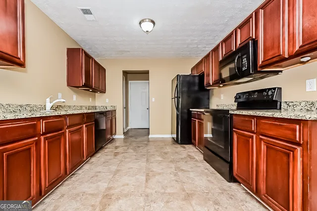 a kitchen with stainless steel appliances granite countertop a stove refrigerator sink and microwave