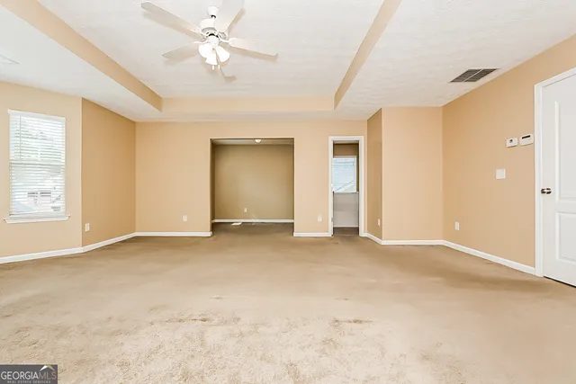 an empty room with windows and fan