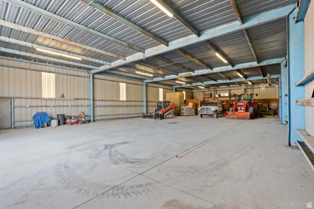 115 East 1600th Street North Santaquin, UT 84655 - Photo 32 of 52 Spacious metal building featuring a concrete floor, corrugated metal ceiling, exposed structural beams, and multiple fluorescent light fixtures