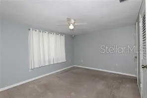 an empty room with windows and fan
