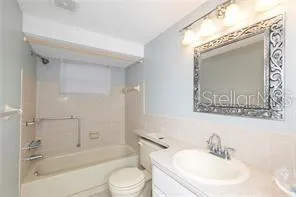 a bathroom with a bathtub shower sink vanity mirror and toilet