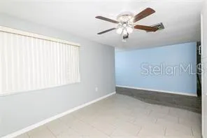 an empty room with windows and fan