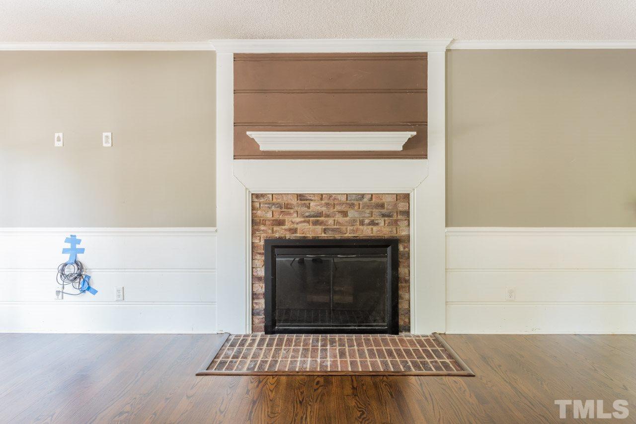 7308 Wilderness Road Raleigh, NC 27613 - Photo 11 of 25 a living room with a fireplace and a rug