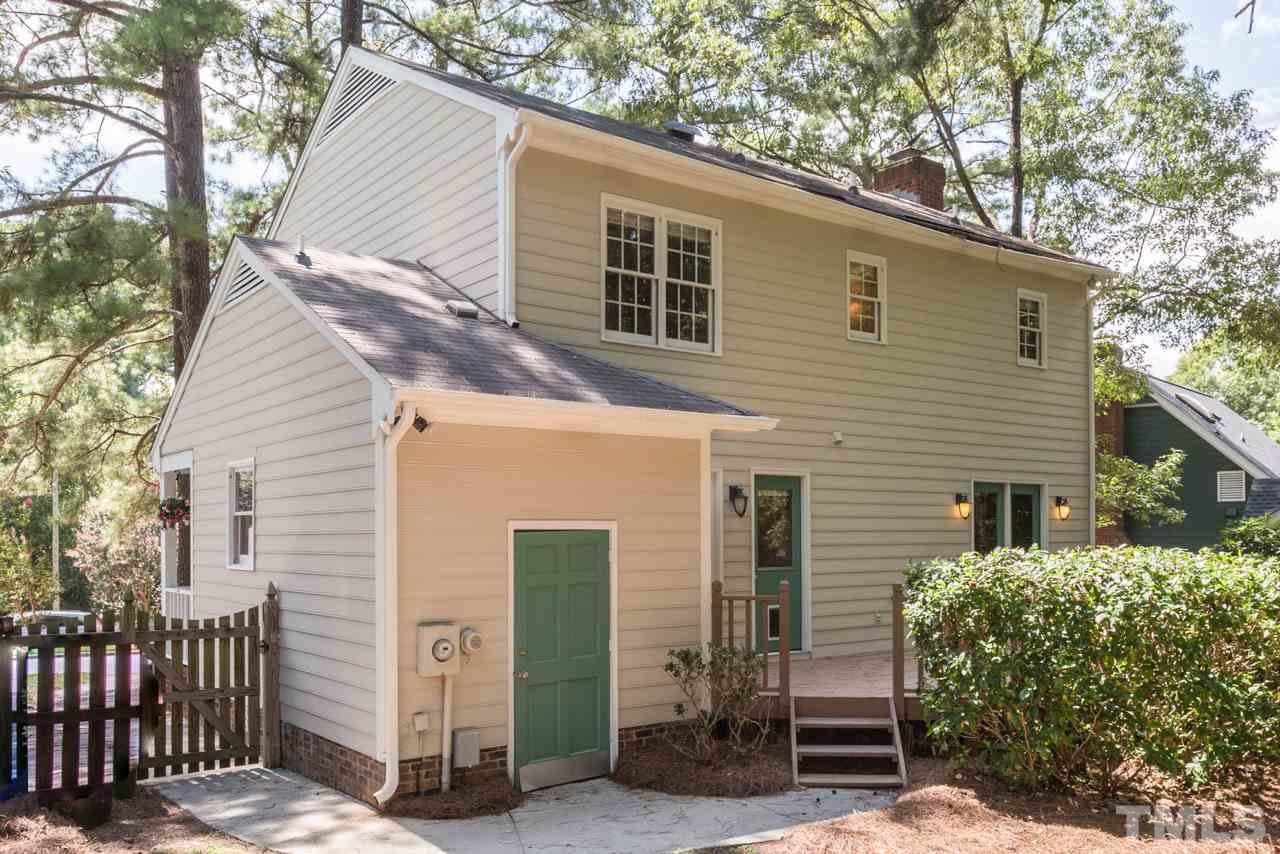 7308 Wilderness Road Raleigh, NC 27613 - Photo 21 of 25 a view of a house with a small yard and wooden fence and large tree