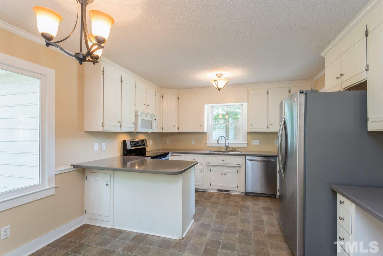 7308 Wilderness Road Raleigh, NC 27613 - Photo 5 of 25 a kitchen with stainless steel appliances granite countertop a sink a stove and a refrigerator