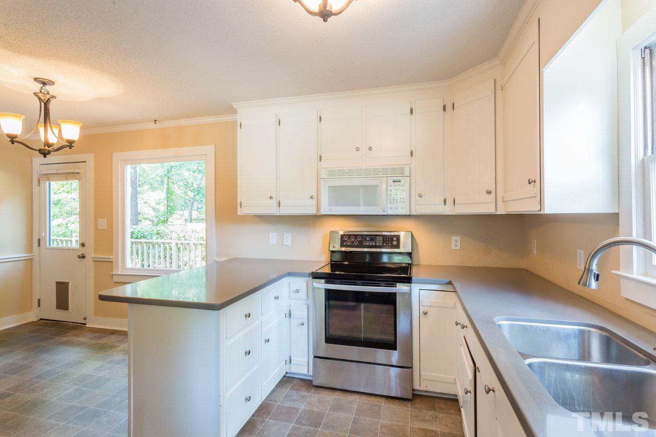 7308 Wilderness Road Raleigh, NC 27613 - Photo 6 of 25 a kitchen with granite countertop white cabinets white stainless steel appliances and sink